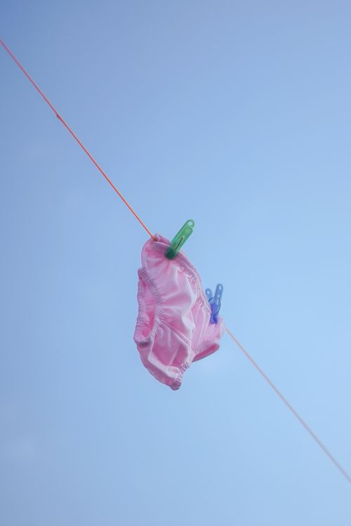 Free A single pink garment hanging on a clothesline against a clear blue sky in Purwokerto, Central Java. Stock Photo