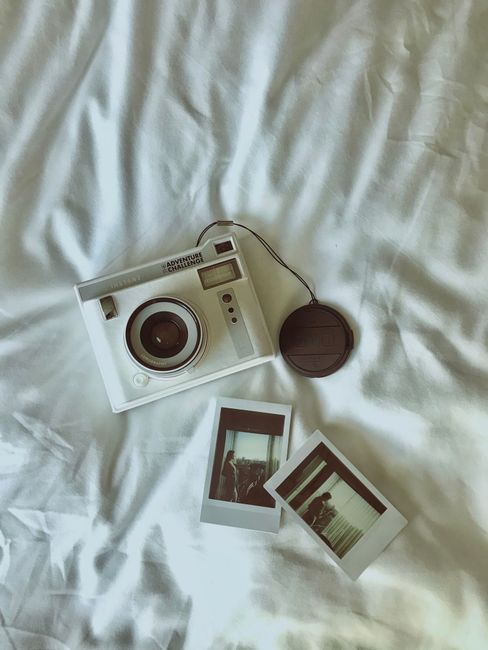 A vintage camera and instant photos captured on a white sheet, creating a nostalgic atmosphere.