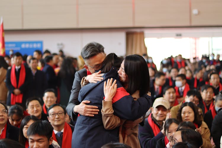 Man And Woman Embracing Student At Ceremony