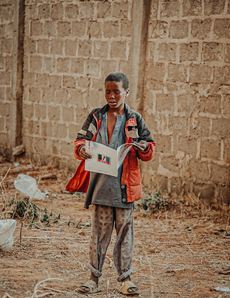 Boy Standing And Reading Book