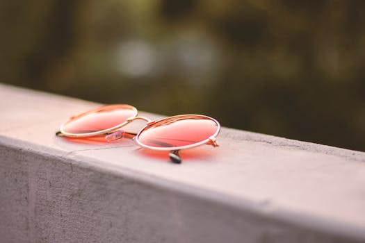 Minimalist close-up of pink tinted round sunglasses resting on a concrete surface.