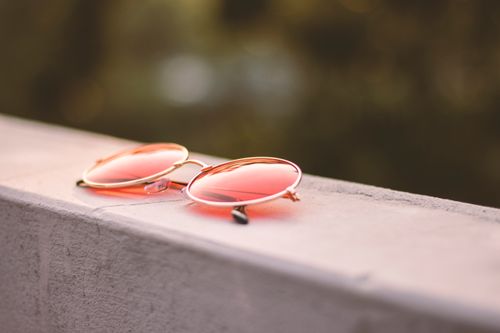 Free Minimalist close-up of pink tinted round sunglasses resting on a concrete surface. Stock Photo
