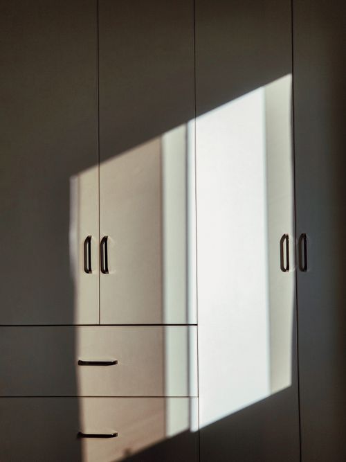 Free Modern cabinet illuminated by sunlight casting geometric shadows. Stock Photo