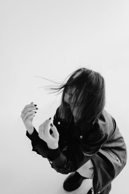 Black and white artistic portrait of a woman crouching with dynamic hair movement.
