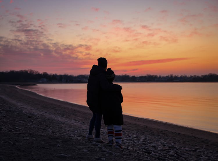 Mother With Child Watching The Sunset On The Beach