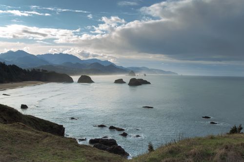Free Beautiful view of Haystack Rock and Oregon coastline at dawn with rocky shores and a serene ocean. Stock Photo