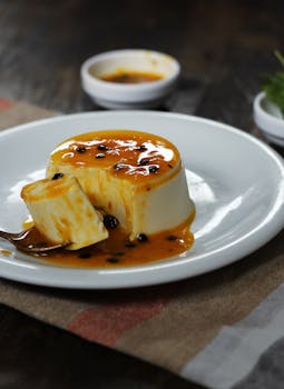 Creamy Brazilian pudding topped with fresh passion fruit sauce on a white plate.