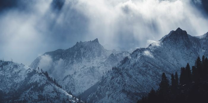 Breathtaking winter view of snow-covered mountains in Leavenworth, WA with dramatic clouds and sunbeams.