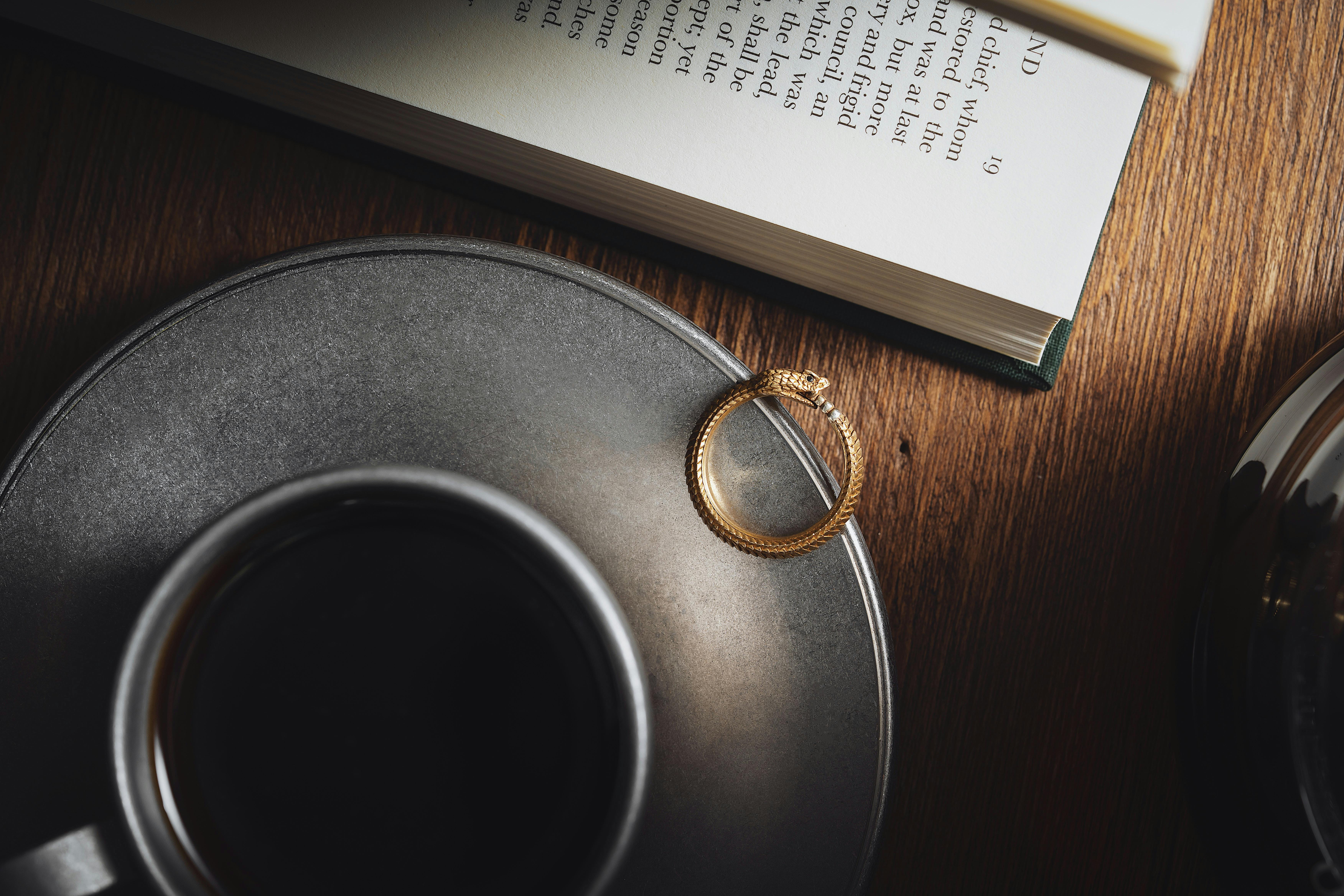 golden snake ring on plate with coffee cup