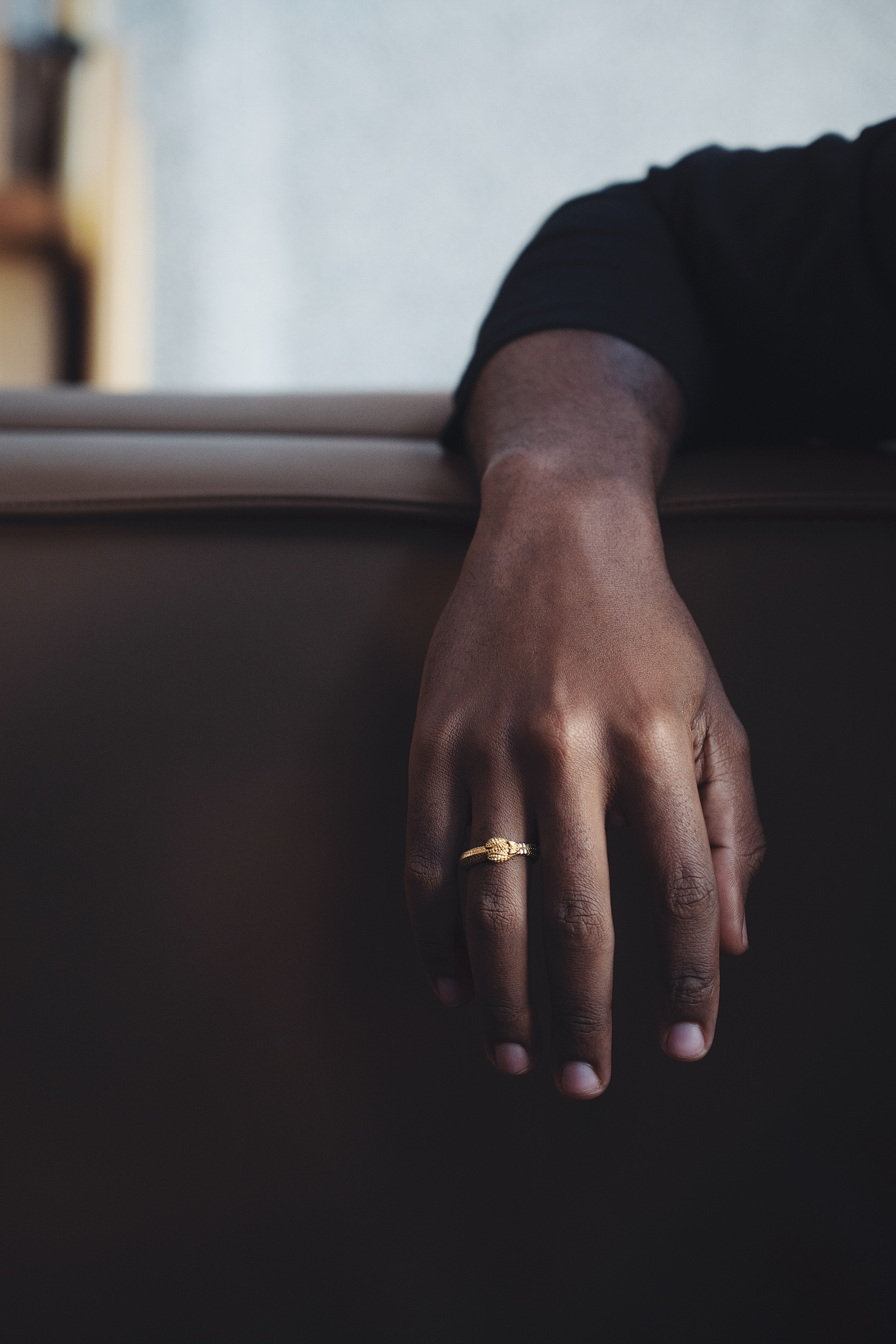 A close-up of an elegant gold snake ring worn on a hand, showcasing exquisite jewelry design.