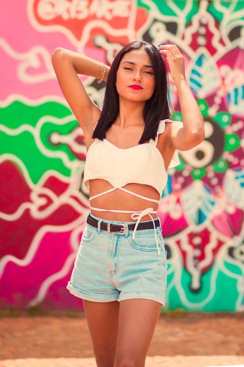 Free Stylish woman in summer outfit posing in front of vibrant graffiti wall. Stock Photo