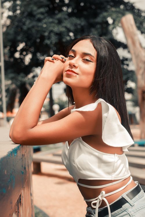 Free Stylish young woman with long brunette hair posing confidently outdoors. Fashionable and vibrant portrait. Stock Photo