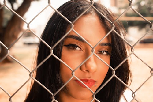 Face of Brunette Seen through Metal Mesh