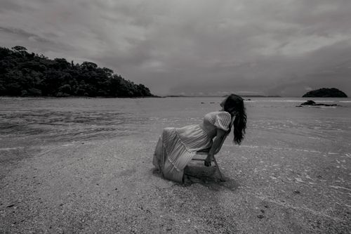 Free A graceful woman posing by the sea in a black and white setting. Stock Photo