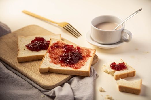 Delicious sliced bread with strawberry jam styled with a hot cup of tea.