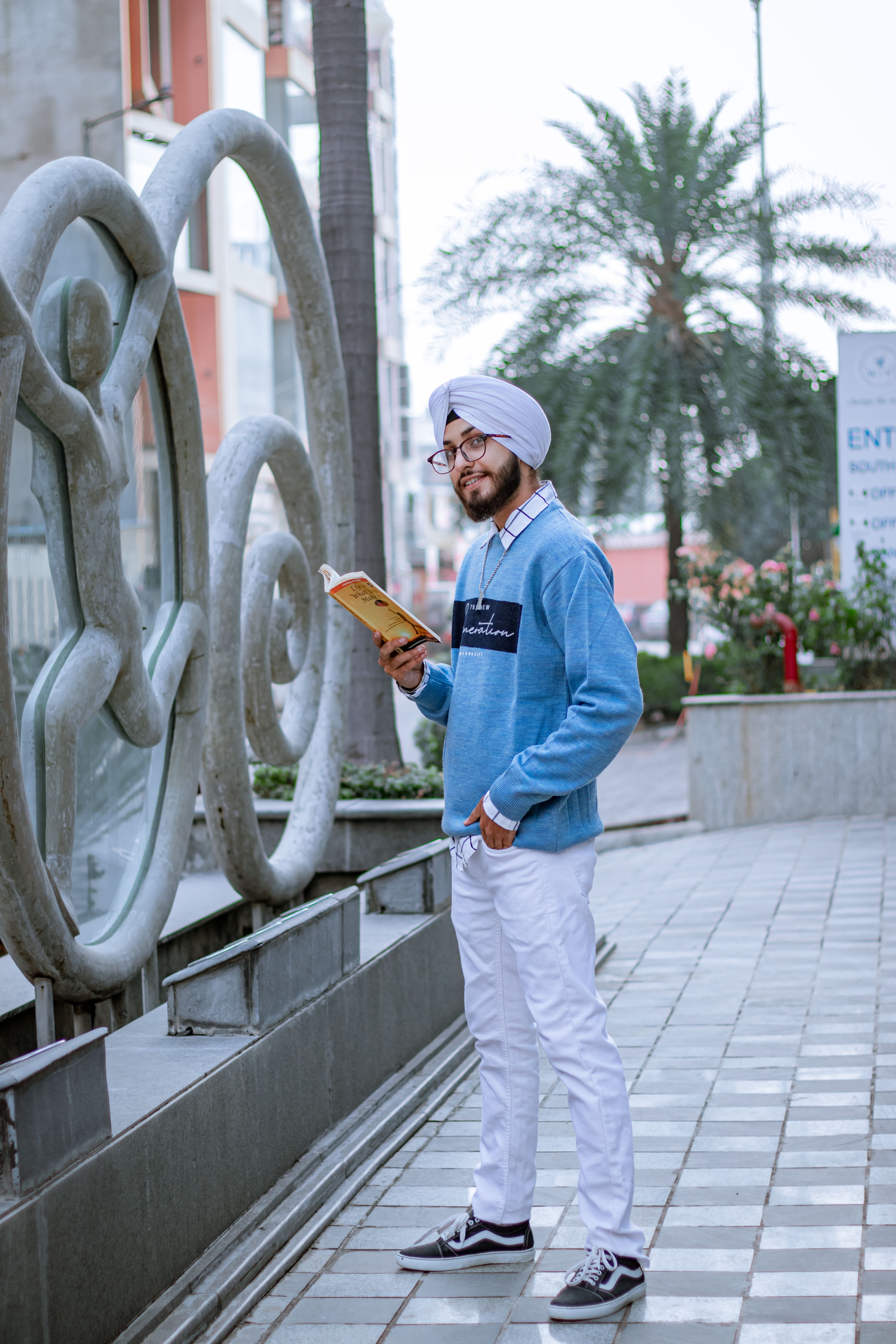 A smiling man in a turban reads a book outdoors in Jaipur, India.