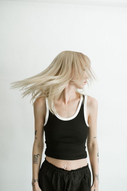 Artistic portrait of a young woman wearing a black top, captured mid-motion.