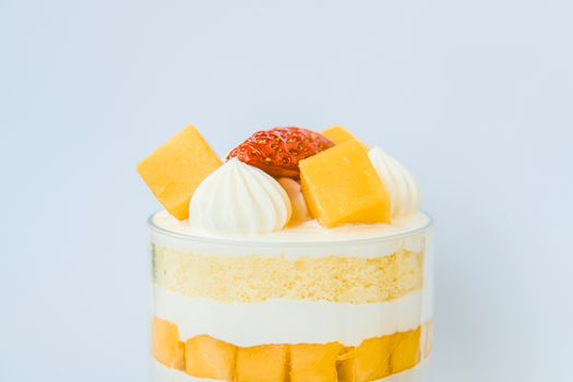 Close-up of a layered mango and strawberry trifle topped with fresh fruit and whipped cream.