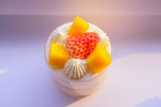 Top view of fruit mousse dessert with fresh mango and strawberry, on a bright background.