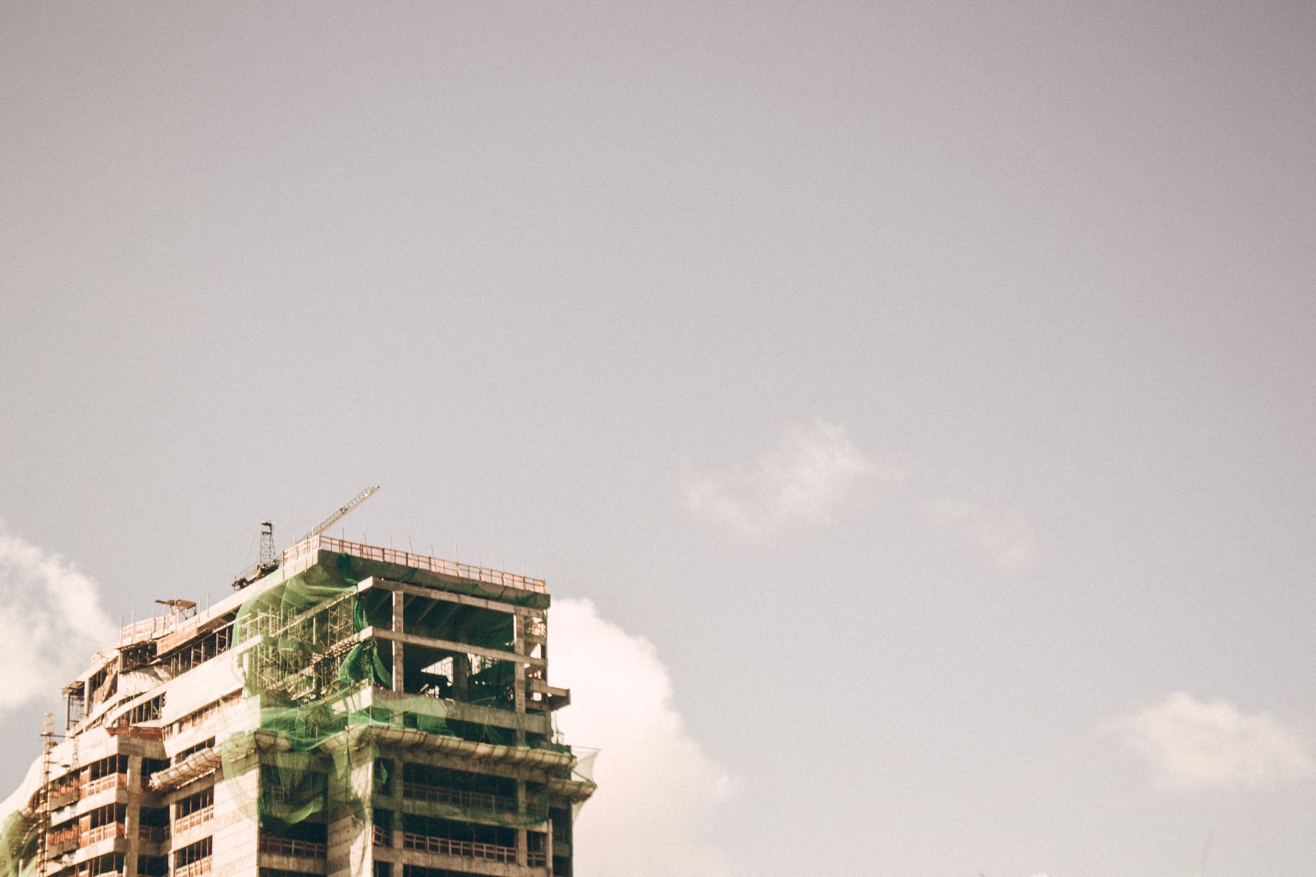 A modern high-rise building under construction against a clear sky in an urban setting.
