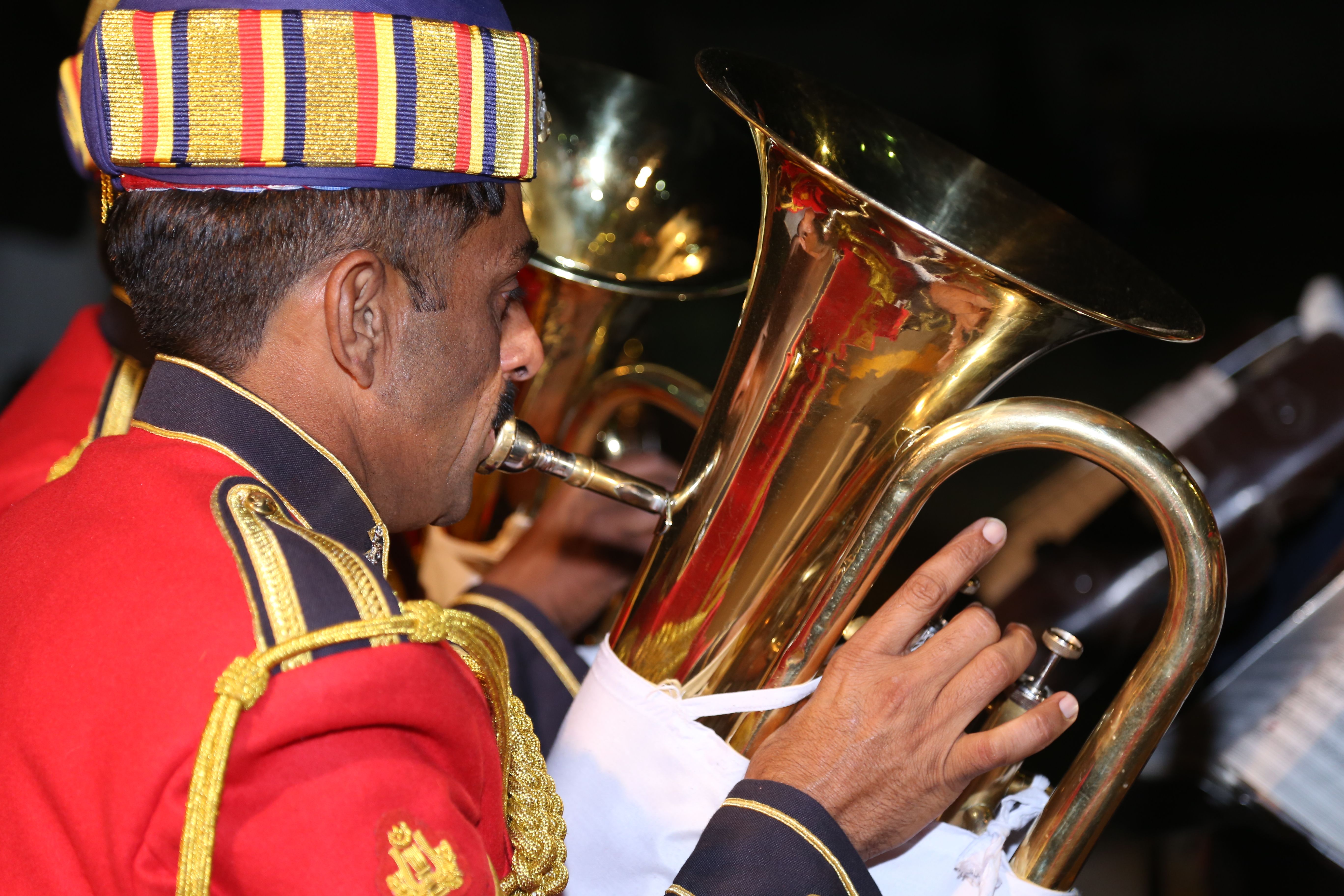 Close-up of a musician in traditional uniform playing a brass tuba, emphasizing cultural music performance.
