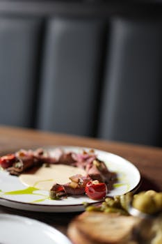 Elegant gourmet beef dish garnished with cherry tomatoes and green sauce.