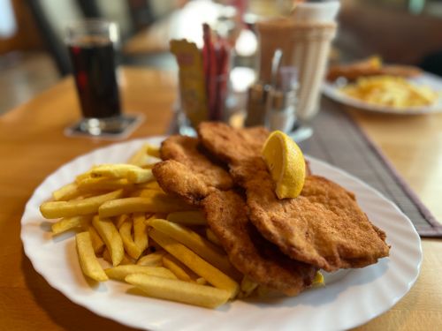 Free Delicious schnitzel with fries and lemon, served at a cozy restaurant table. Stock Photo