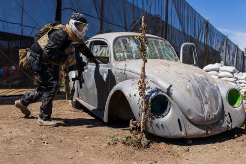 Free Airsoft player with protective gear hiding behind an abandoned car during a match in León, Gto., Mexico. Stock Photo