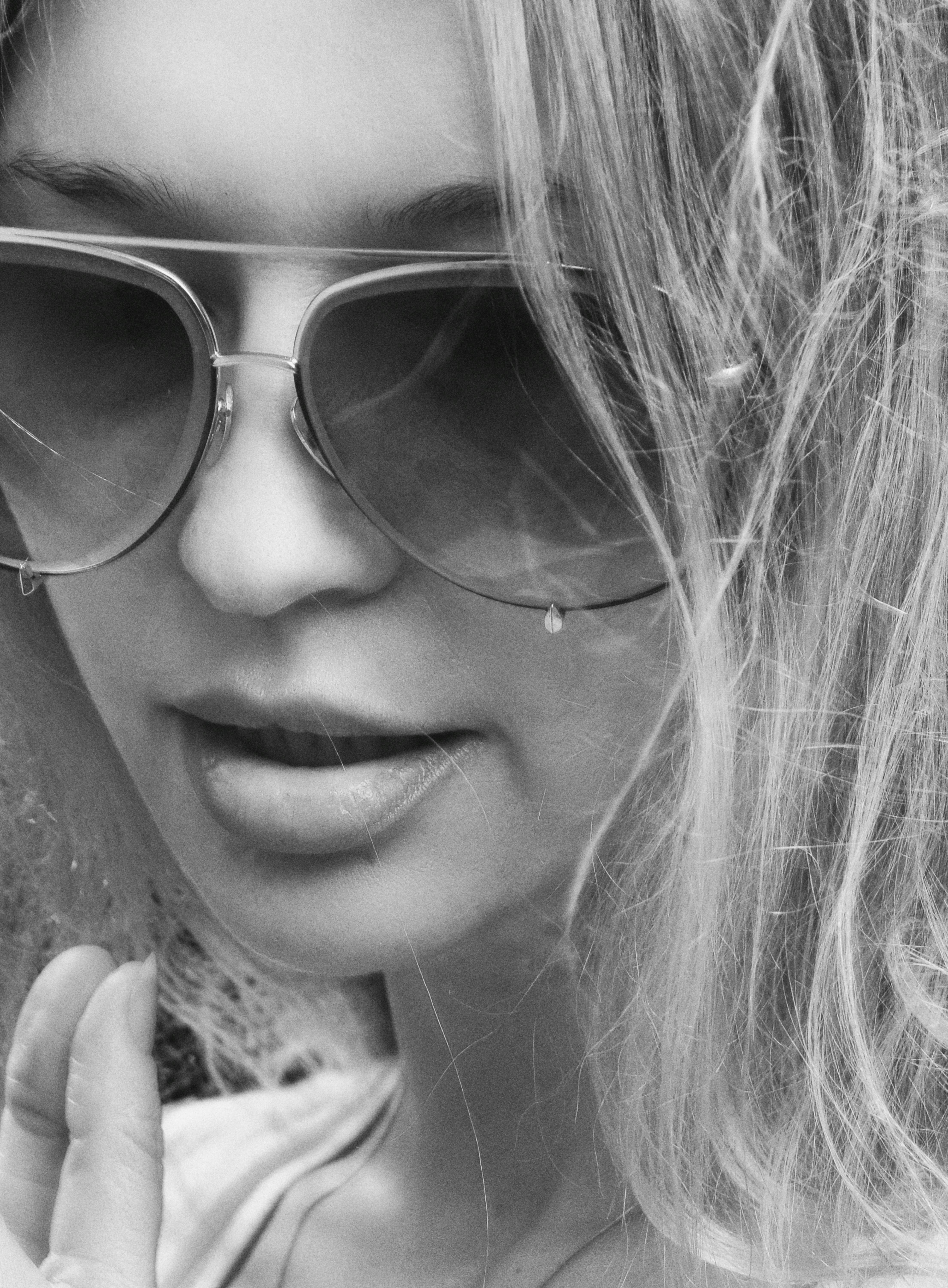 Close-up black and white portrait of a woman wearing sunglasses, highlighting fashion.
