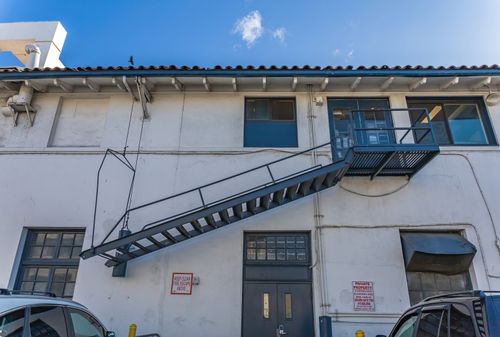 Free An outdoor metal fire escape staircase on a white urban building under a clear blue sky. Stock Photo