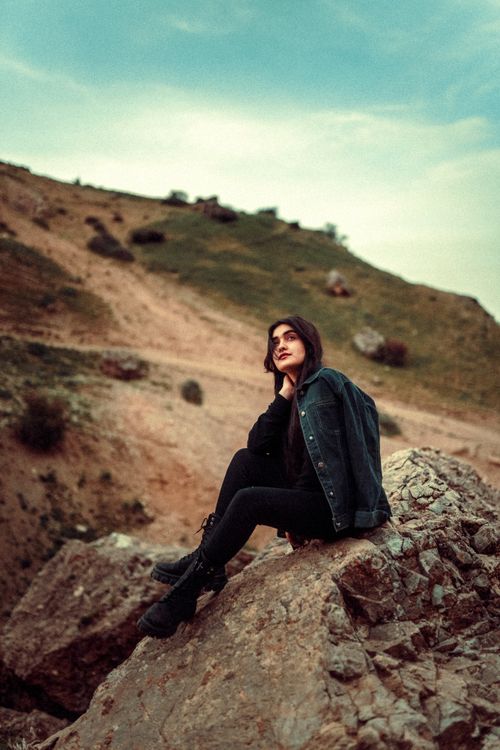 Free A woman in black boots and jacket poses on a rocky terrain in Iran's scenic outdoors. Stock Photo