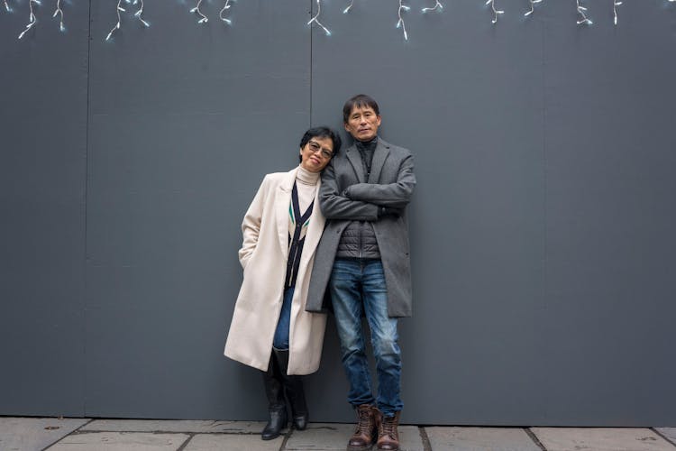 Adult Married Couple Standing Against The Wall In City 