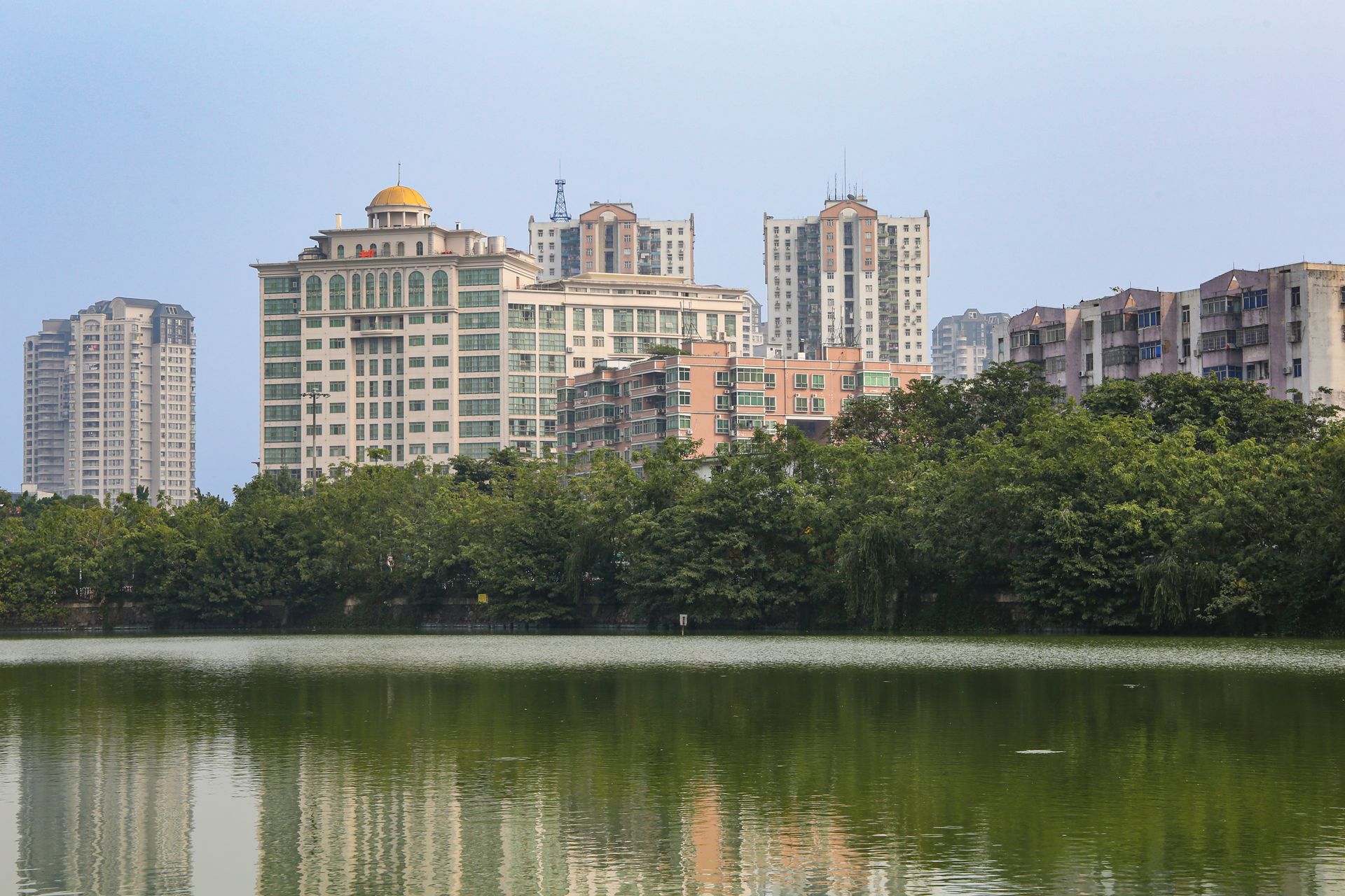 Cityscape of Hefei showcasing modern architecture and a tranquil pond reflection.