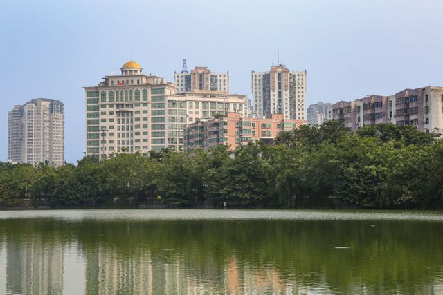 Cityscape of Hefei showcasing modern architecture and a tranquil pond reflection.