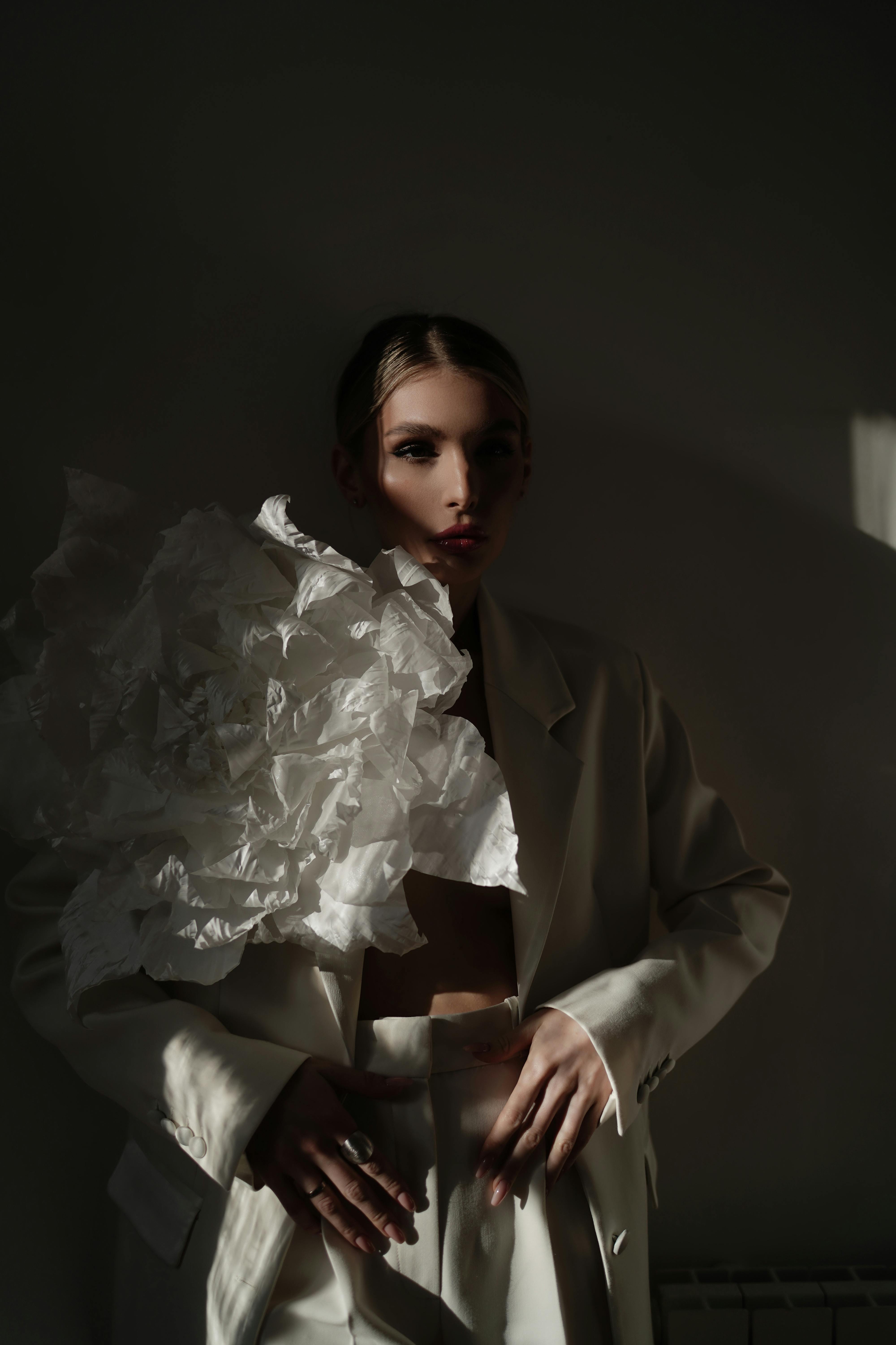Striking portrait of a woman in a white suit with bold shadows and artistic styling.