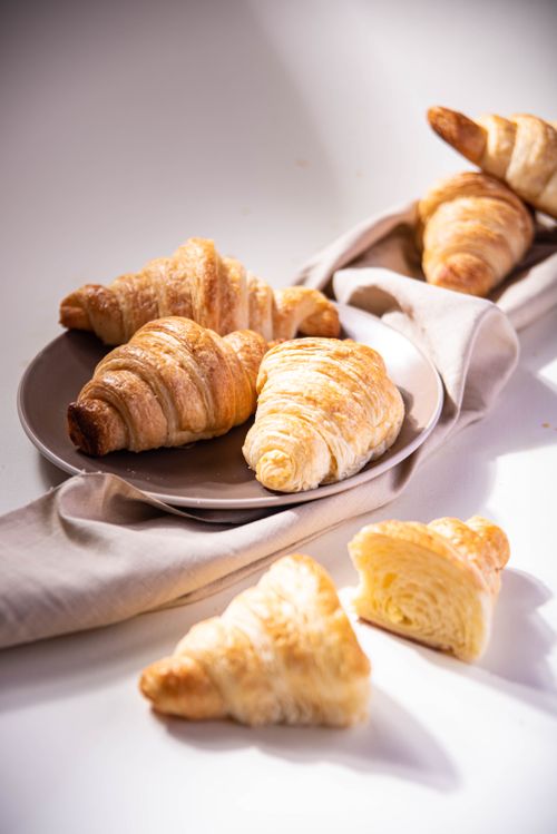 Free Close-up of freshly baked croissants on a plate, showcasing their flaky texture and golden hues. Stock Photo