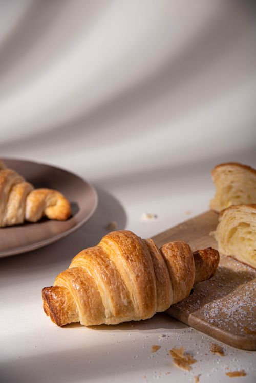 Free Delicious golden croissants on a wooden board, perfect for breakfast or a light snack. Stock Photo