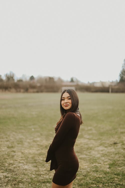 Young Brunette Woman in Dress on Empty Field