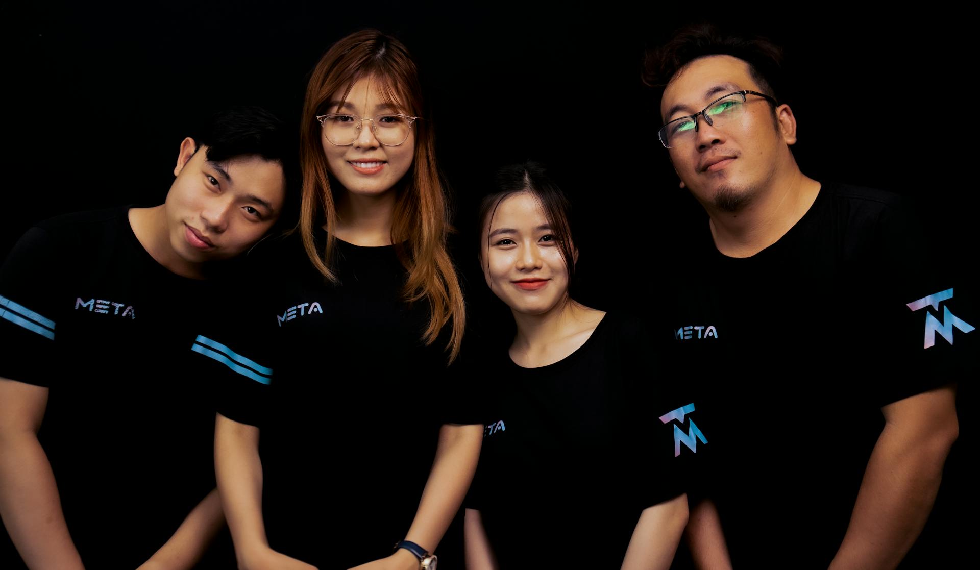 Four diverse young adults in META logo T-shirts against a black background.