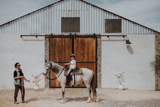 A young girl rides a horse with her mother nearby at a farm in San Juan del Rancho, Mexico.
