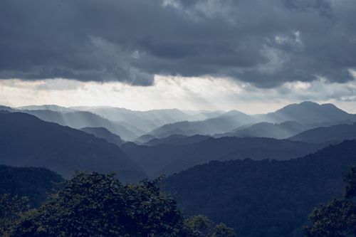 Free A stunning aerial view of a mountain range with dramatic clouds and sun rays cascading over the landscape. Stock Photo