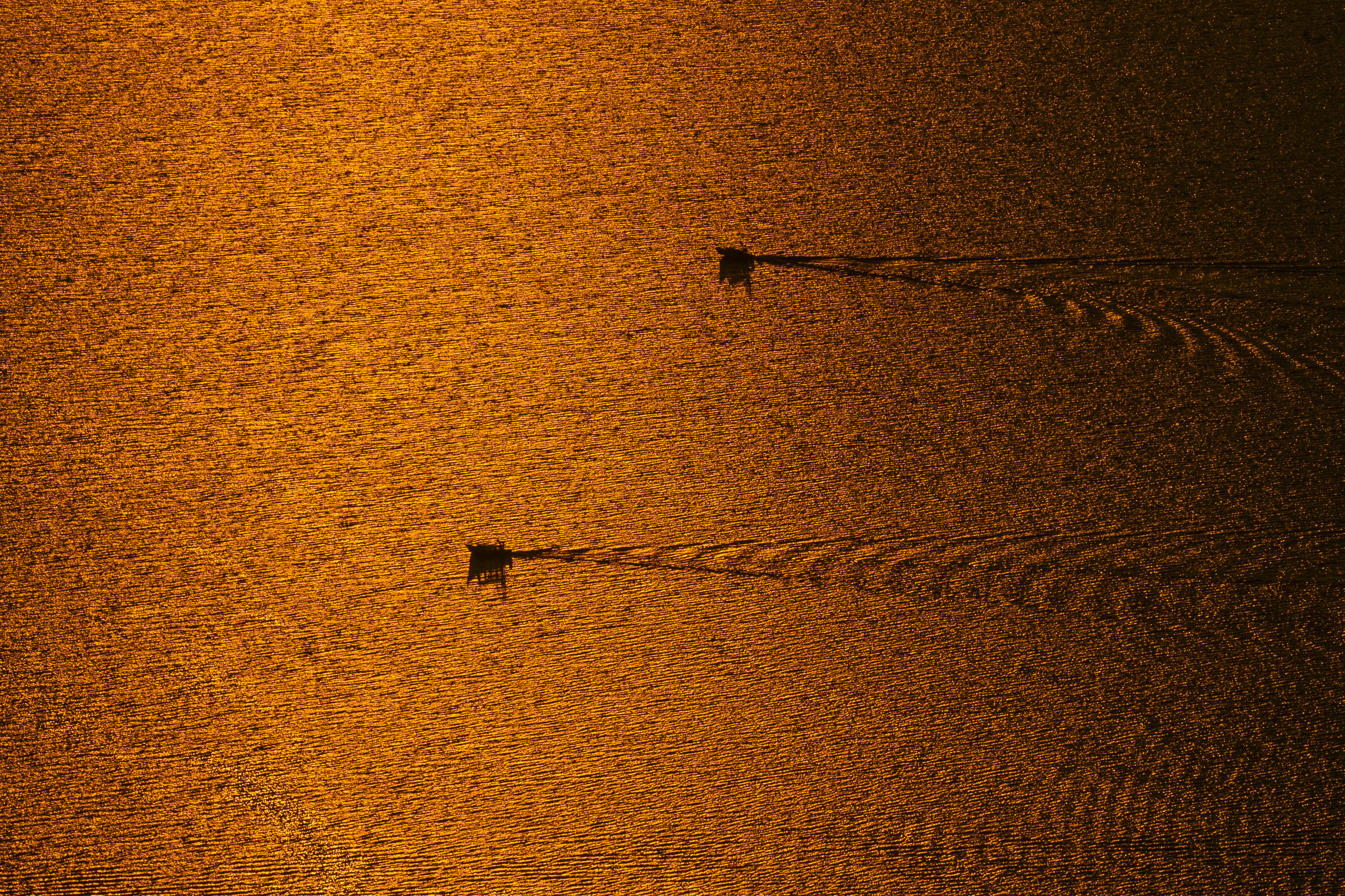 Aerial view of boats on a shimmering lake at sunset in Santa Clara La Laguna, Guatemala. - Lago Atitlán