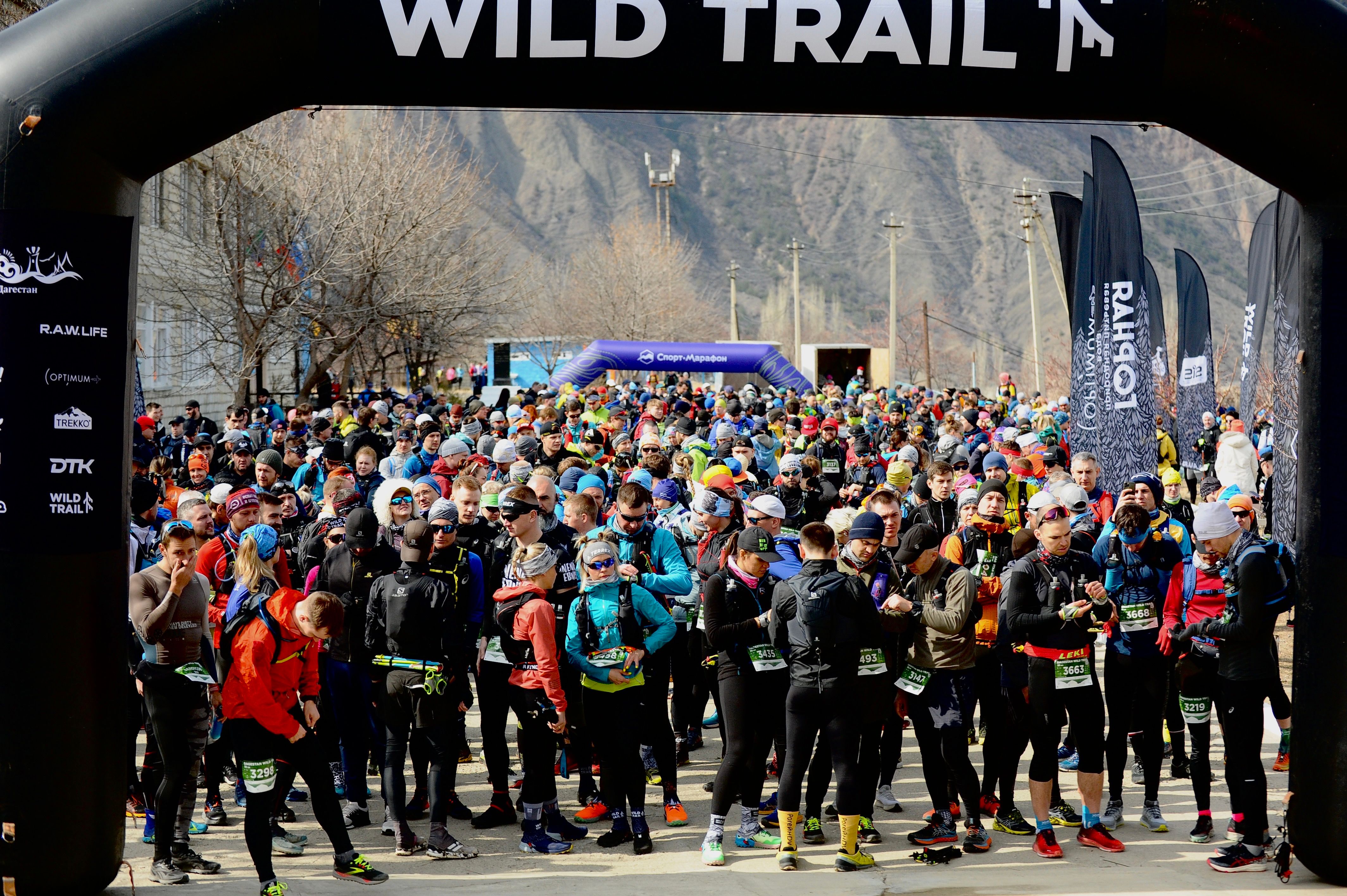 Départ d'un trail — plusieurs centaines de coureurs sous l'arche Wild Trail