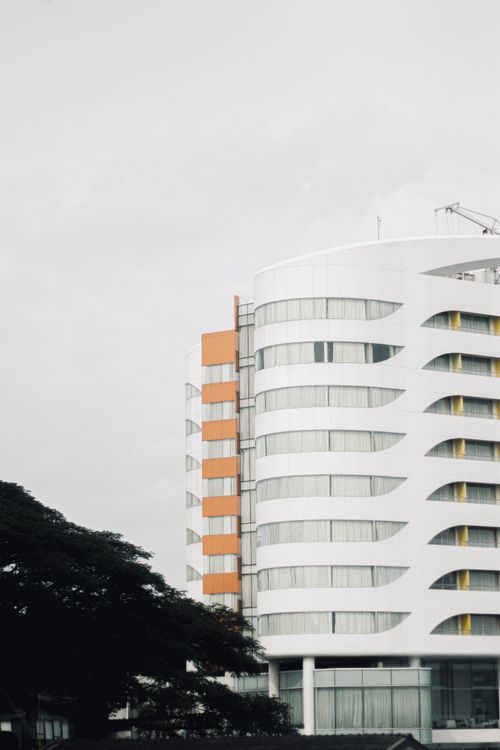 Free A futuristic building exterior with a unique curved design against a cloudy sky. Stock Photo