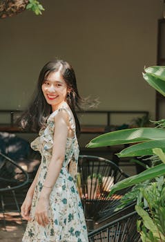 Happy woman in a floral dress enjoying a sunny day outdoors.