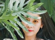 这幅宁静的女子肖像，部分被郁郁葱葱的怪物树叶遮住，散发着美丽与宁静的气息