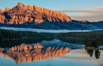 荒野中，宁静的湖泊倒映着日出时雄伟的山脉