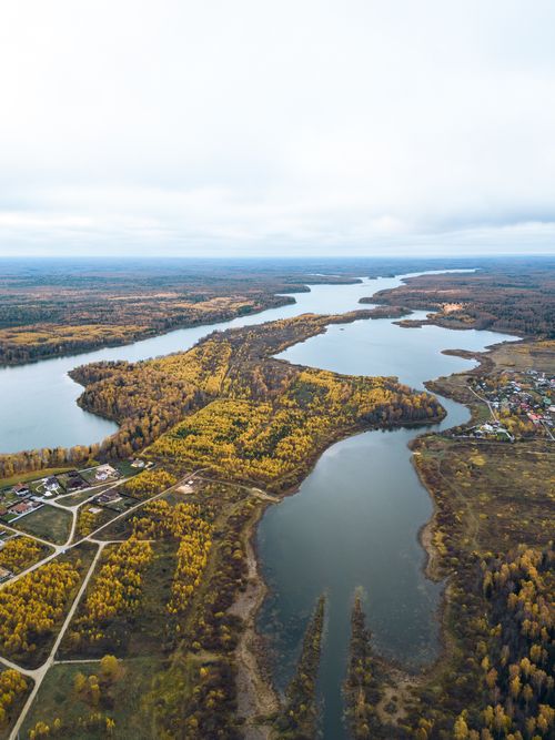 Free A breathtaking aerial view of a serene river winding through a vibrant autumn landscape in a rural area. Stock Photo
