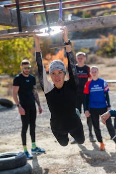 Woman showcasing strength and determination on an outdoor obstacle course with supportive onlookers.