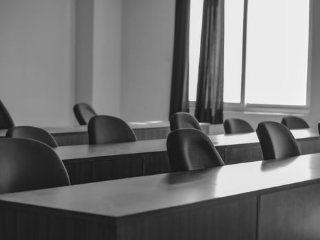 Monochrome image of a quiet and minimal office space with empty chairs and desks.